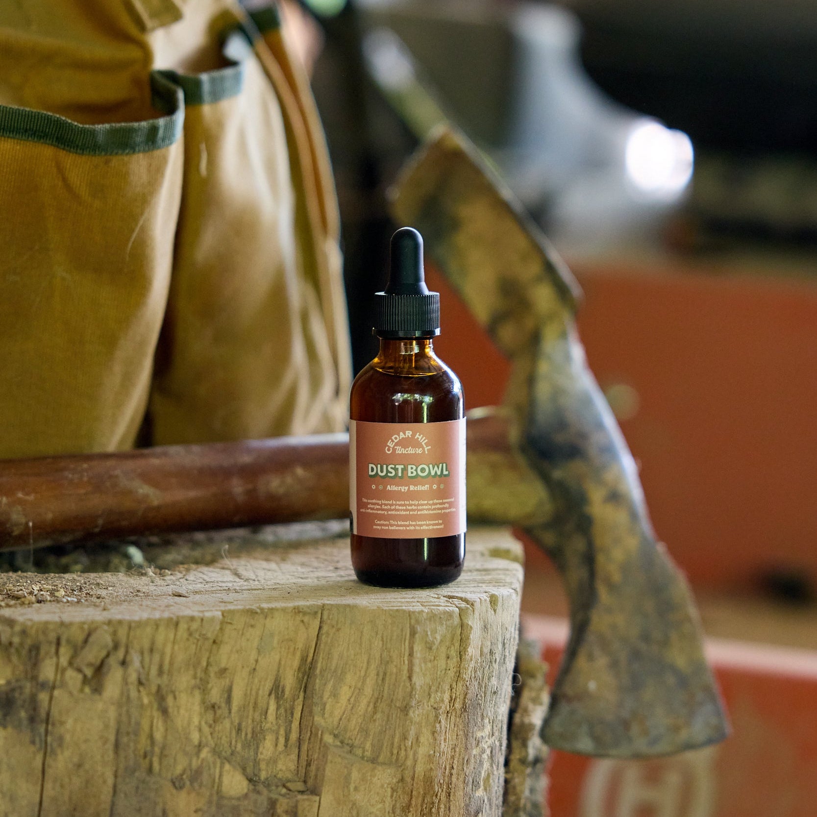 Bottle of 'Dust Bowl Allergy Tincture' on a wooden block with a workshop background
