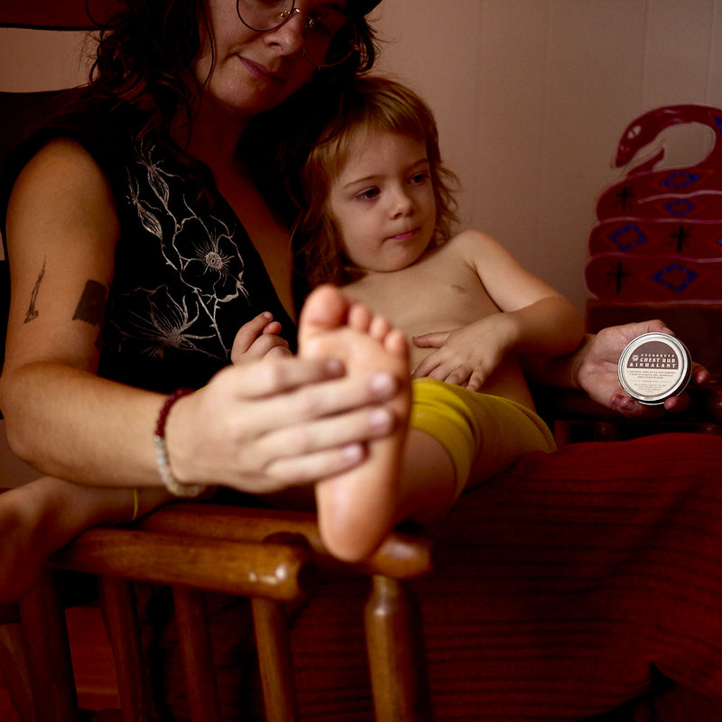 Mother applies Evergreen chest rub inhalant to her child's foot.

