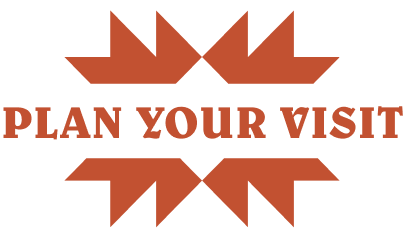An orange graphic with the words 'PLAN YOUR VISIT' in bold uppercase letters, flanked by symmetrical abstract arrow-like shapes above and below, on a white background.