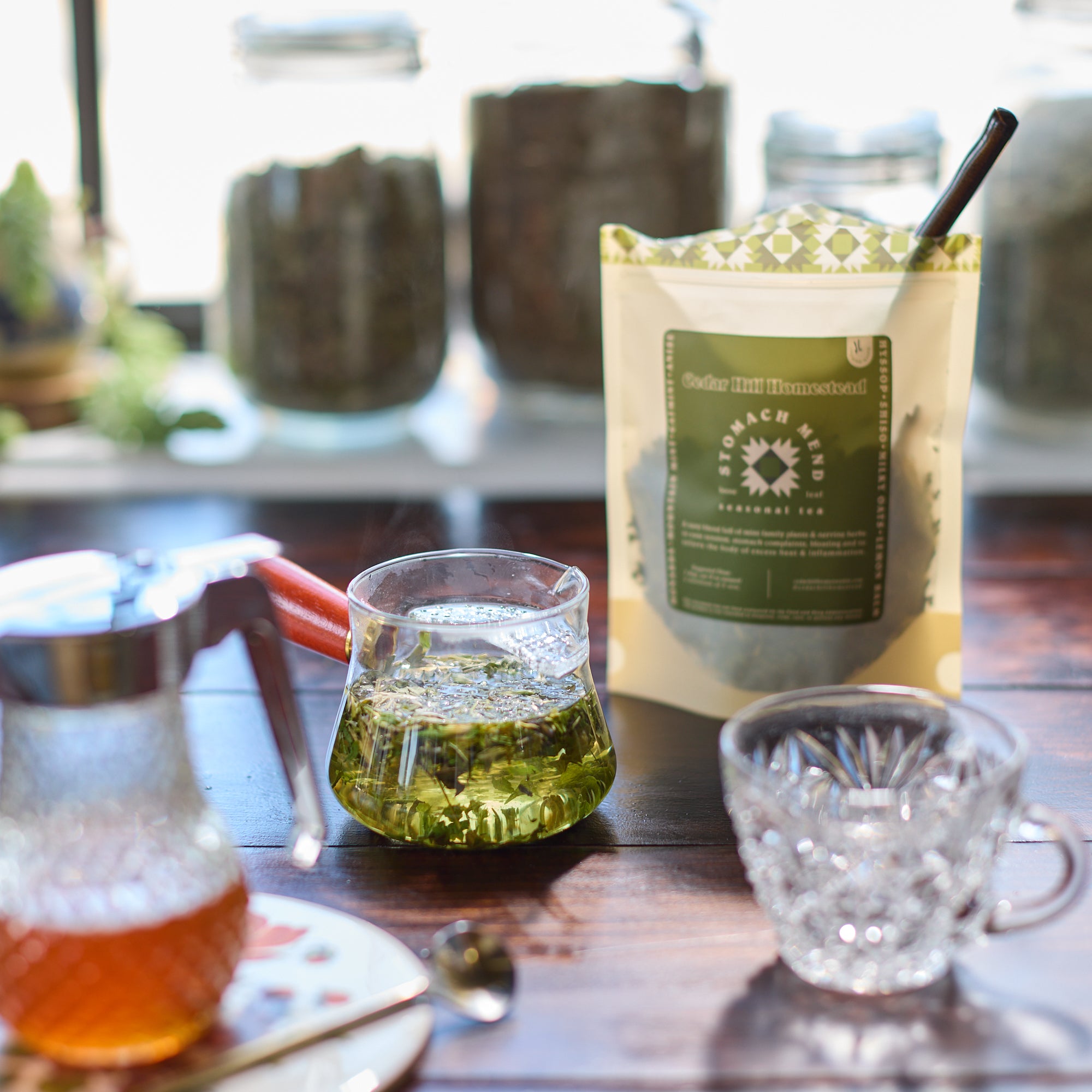 Tea-making setup with a glass of green tea, tea leaves, and packaging on a wooden table.